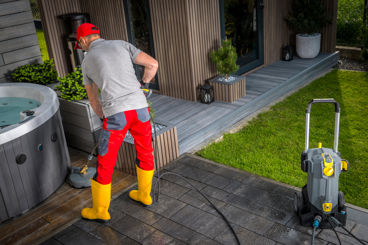 The cleaner is using a vacuum to clean the exterior of a house.