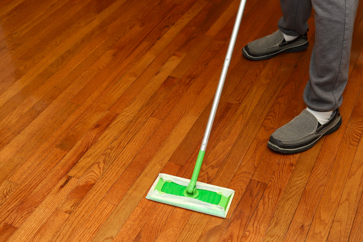 A cleaner is mopping the floor to maintain good hardwood floors during cold weather.