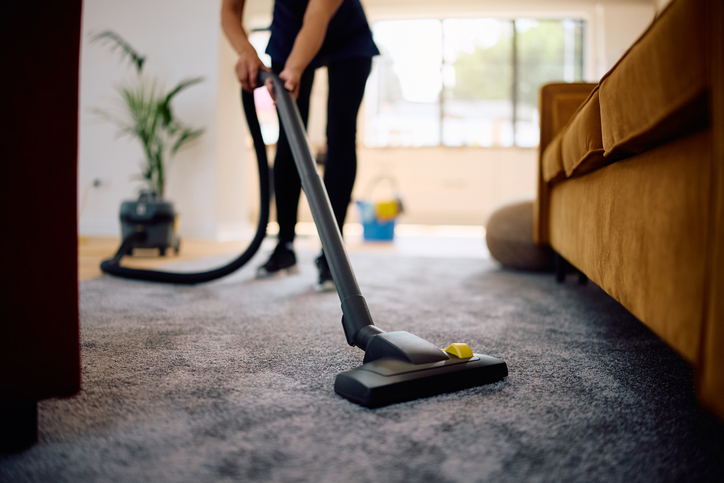 A cleaner is vacuuming the carpet, providing a professional deep cleaning before the season changes.